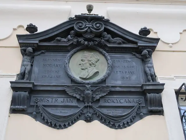 The image shows a plaque on the side of a building in Prague, Czech Republic. The plaque is made of...