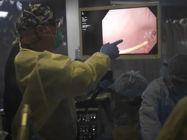 The image shows a group of people in scrubs and masks working on a computer screen in an operating...