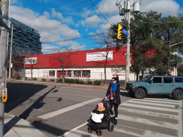 The image shows a woman crossing the street with a baby in a stroller. She is wearing a black dress...