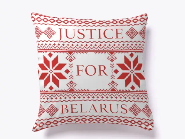 The image shows a red and white pillow with the words "Justice for Belarus" printed on it against a...