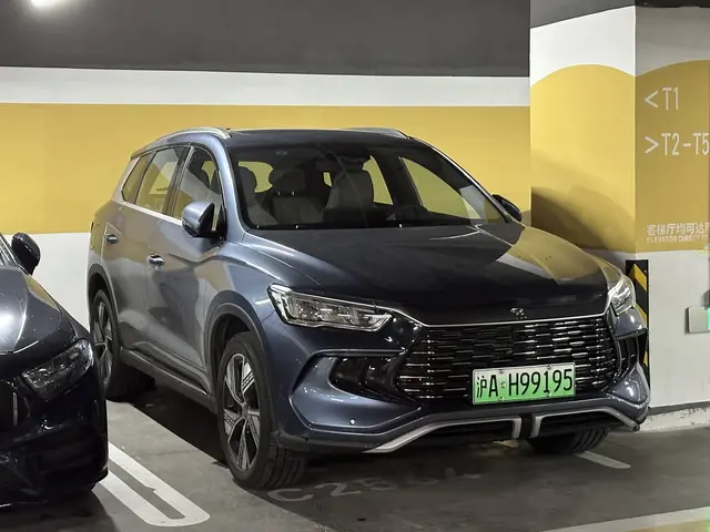 The image shows two cars parked next to each other in a parking garage, with a wall in the...