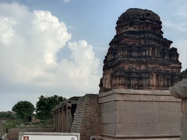 The image shows a sign in front of a temple in the middle of a field, surrounded by monuments,...