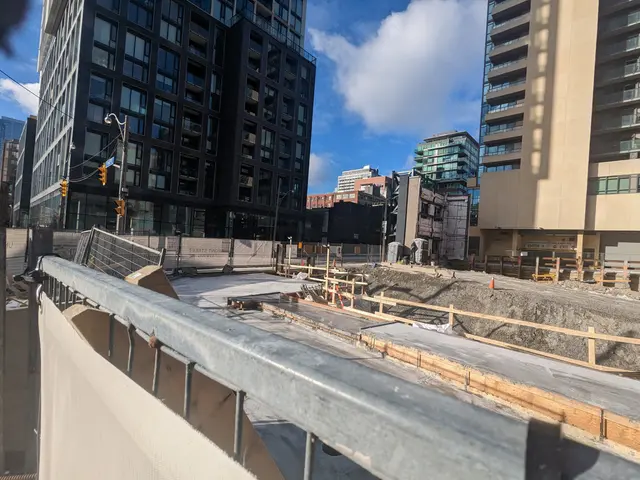 The image shows a construction site with a large building in the background, surrounded by...