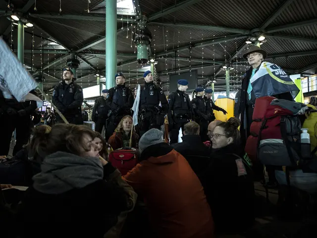 The image shows a group of people standing in front of a crowd of people, some of whom are wearing...