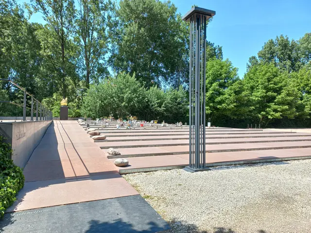 The image shows a large metal sculpture in the middle of a park surrounded by trees and bushes. On...