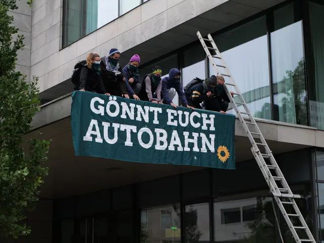 The image shows a group of people standing on top of a building, holding a banner with text on it....