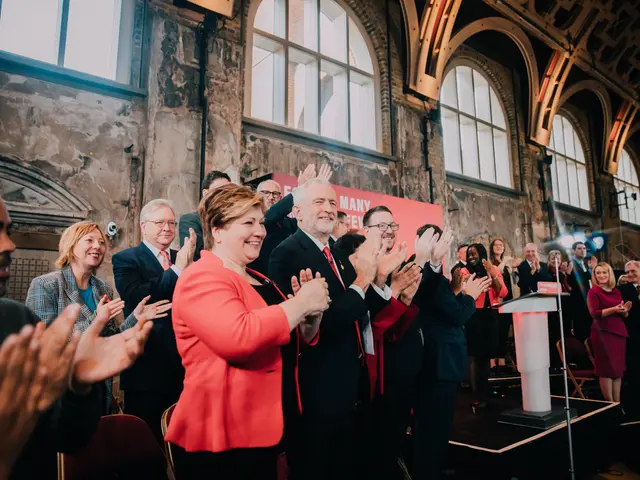 The image shows a group of people standing in front of a crowd, clapping their hands in...