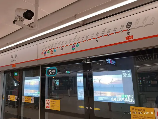 The image shows a train at a station with a CCTV camera mounted on the ceiling. The train is...