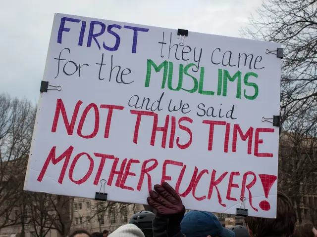 The image shows a group of people wearing caps and gloves, holding a sign that reads "First they...