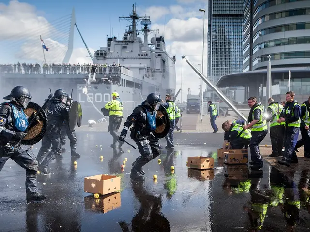 The image shows a group of police officers in riot gear walking down a street next to a large ship....