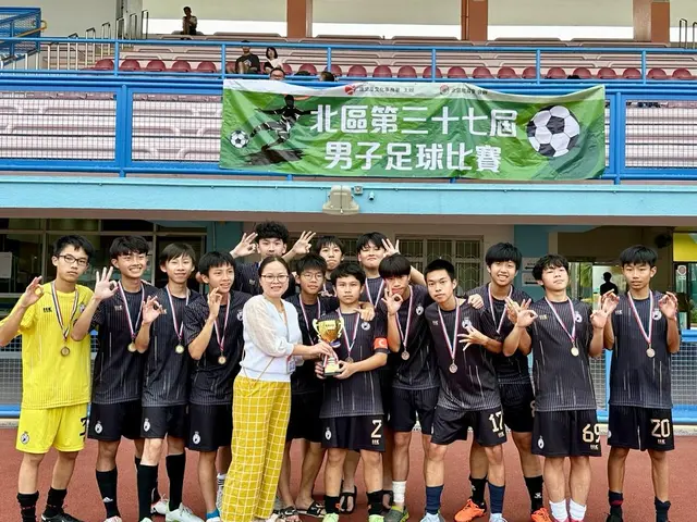The image shows a group of young men standing next to each other on a soccer field, wearing medals...