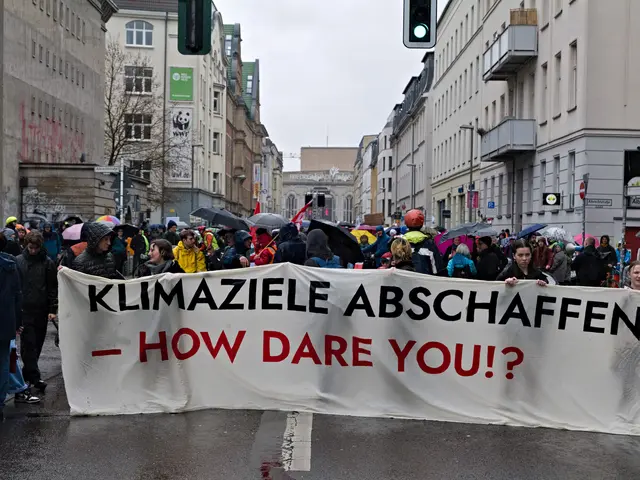 The image shows a group of people walking down a street, holding a banner that reads "Klimaziele...