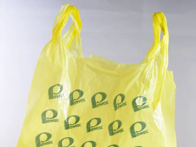 The image shows a yellow plastic shopping bag with a green logo on it against a white background.