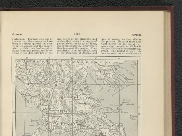 The image shows an open book with a map of Greece on it, placed on a black surface. The book...