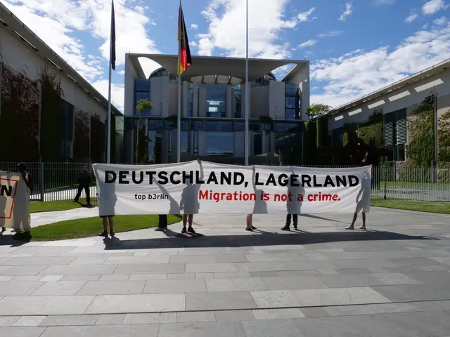 The image shows a group of people holding a banner that reads "Deutschland, Lagerland Migration is...