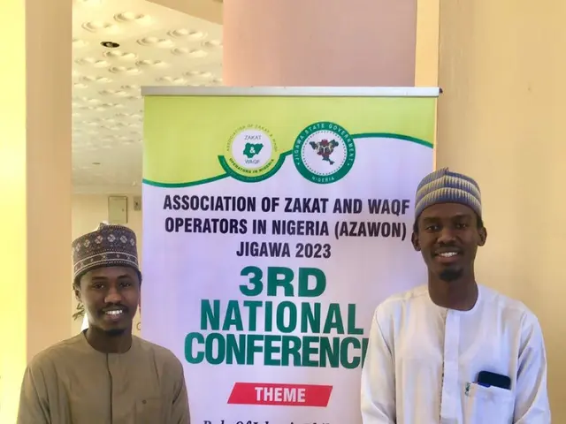 The image shows two men standing next to each other in front of a banner that reads "3rd National...