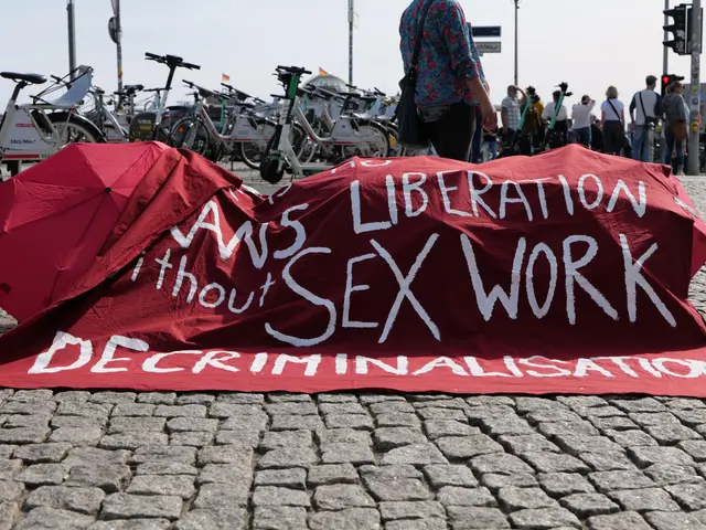 The image shows a group of people standing on the ground, some of them holding umbrellas, with a...