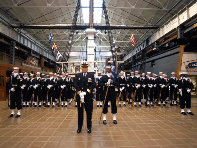 The image shows a group of men in uniform standing next to each other in a large room. They are...