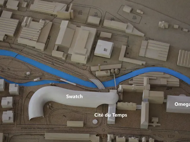 The image shows a model of a city with a river running through it, featuring buildings, roads, and...