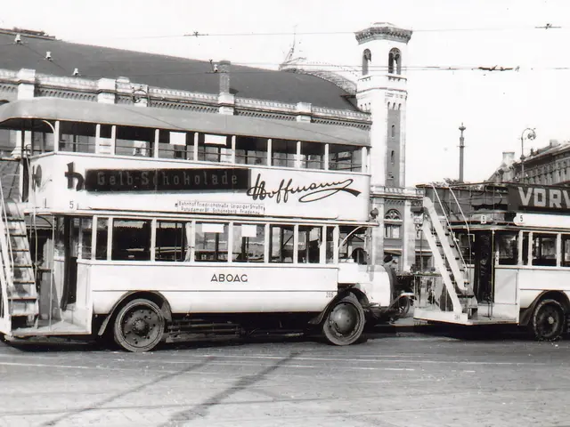 The image shows a black and white photo of two double decker buses parked next to each other on the...