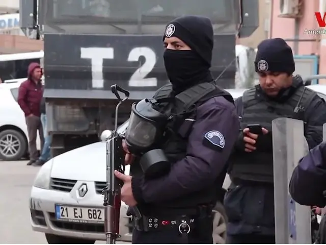 The image shows a group of police officers standing next to each other on a street, wearing...
