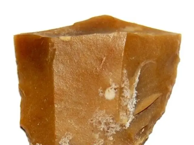 The image shows a piece of brown soap sitting atop a white surface.