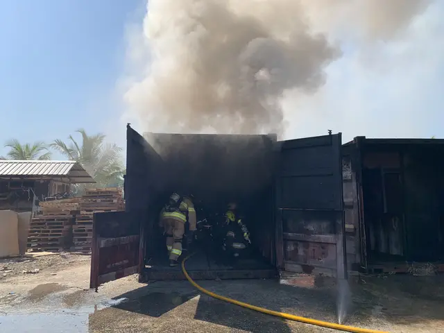 The image shows a group of firefighters wearing helmets and holding pipes in their hands, standing...