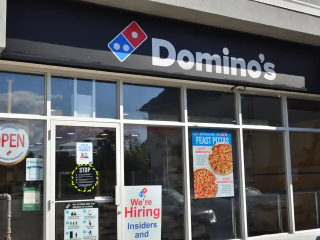 The image shows a Domino's Pizza restaurant with glass walls and doors, posters with text and...