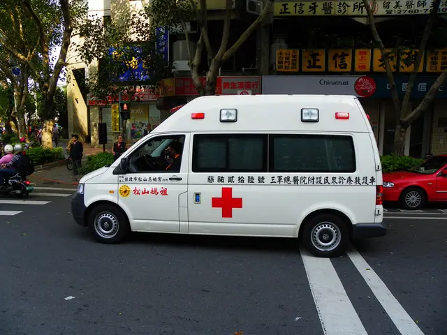 The image shows an ambulance parked on the side of the road, surrounded by people wearing helmets...