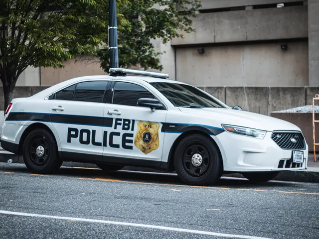 The image shows a police car parked on the side of the road in front of a building. The car is...