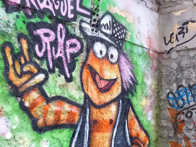 The image shows a red car parked in front of a wall with graffiti on it. The graffiti is colorful...