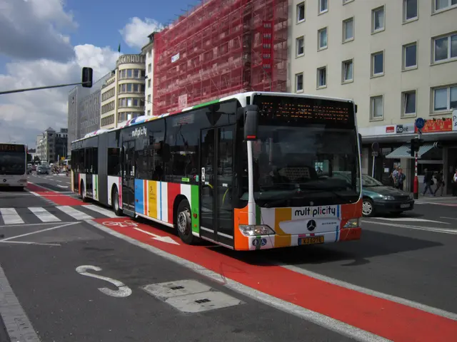 The image shows a city bus driving down a street lined with tall buildings. There are people...