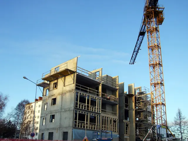 The image shows a construction site with a large building under construction, surrounded by a...