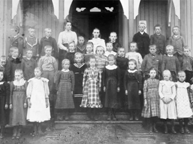 The image shows a black and white photo of a group of children standing in front of a building with...