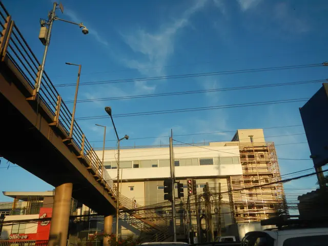 The image shows a city street with cars parked on the side of it, a bridge with railings, light...