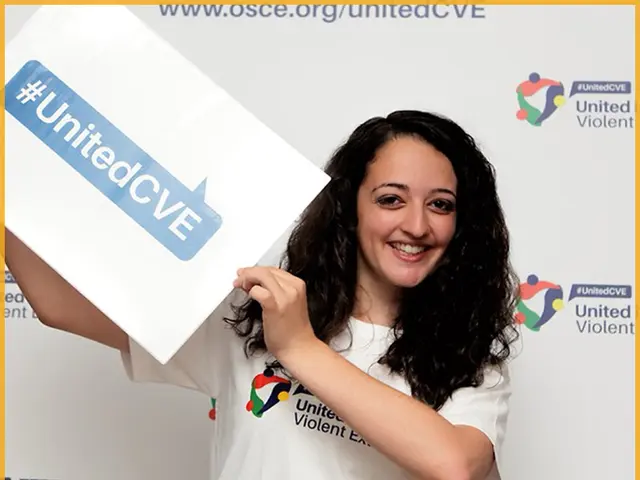The image shows a woman with a bright smile on her face, holding up a sign that reads "Emerging...