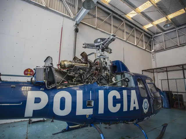 The image shows a police helicopter parked inside of a hangar, with its engine visible. The walls...