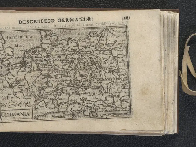 The image shows an open book with a map of Germany on it, placed on a black surface. The book is...