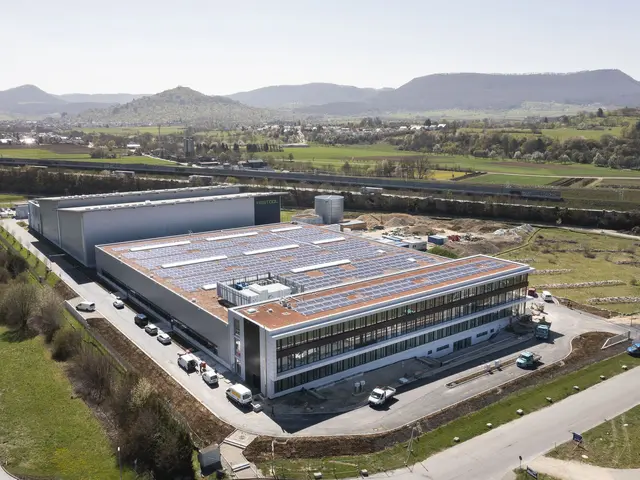 The image shows an aerial view of a large building with solar panels on the roof, surrounded by...