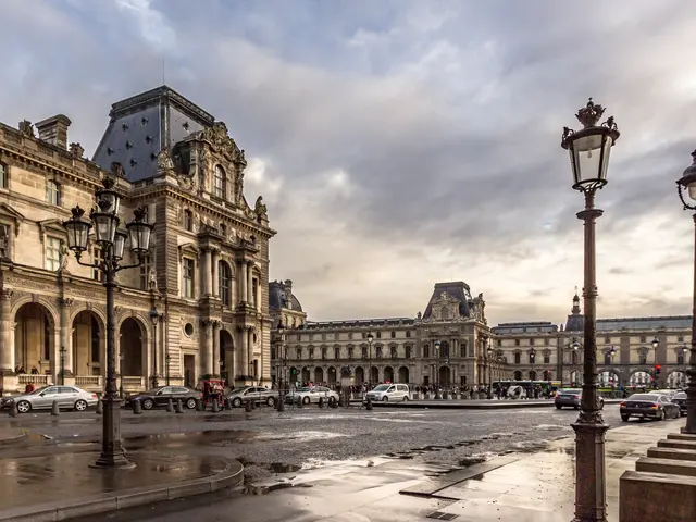 The image shows the Louvre Museum in Paris, France, with its iconic buildings, street poles, street...