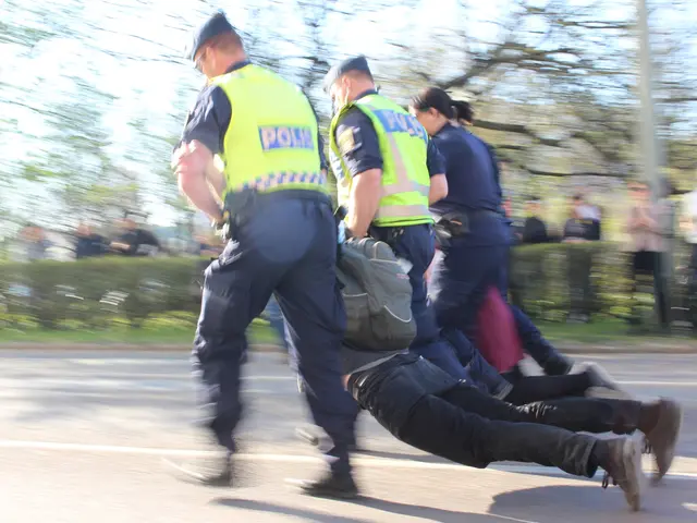 The image shows a group of police officers pushing a man down the street. The man is wearing a bag...
