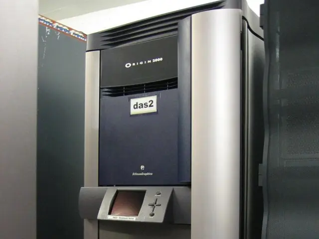 The image shows a large machine sitting in the middle of a room, with a wall on the left side and a...