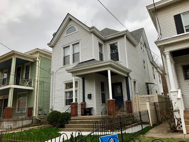 The image shows a row of houses with windows, doors, pillars, railings, steps and roofs, surrounded...