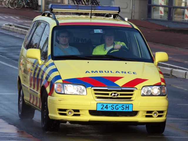 The image shows a yellow ambulance driving down the street with two people inside. On the left side...