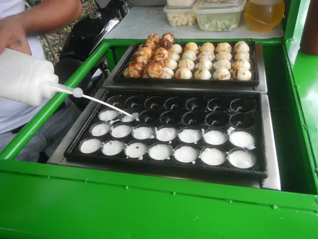 The image shows a man pouring milk from a bottle into a tray of food on top of a green table. On...