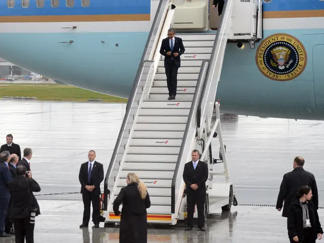 The image shows President Obama boarding Air Force One at the airport, surrounded by a group of...