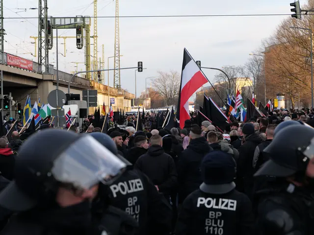 The image shows a large group of police officers standing in front of a crowd of people, some of...