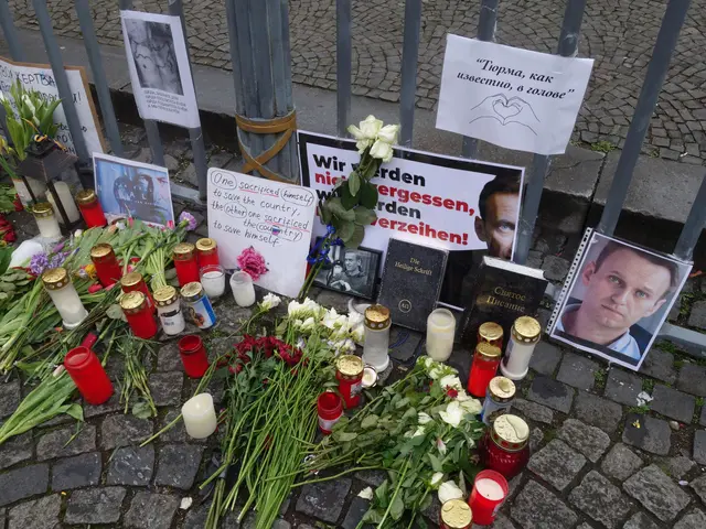 The image shows a memorial in Berlin, Germany, with flower bouquets, candles, photo frames, and...