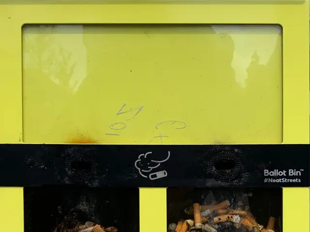 The image shows a yellow recycling bin filled with cigarette butts sitting on top of a sidewalk....