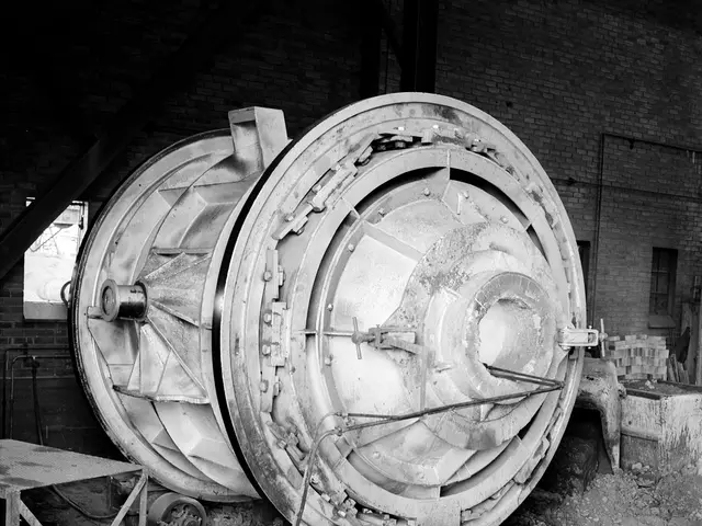 The image shows a large machine sitting in the middle of a room, surrounded by a table on the left...